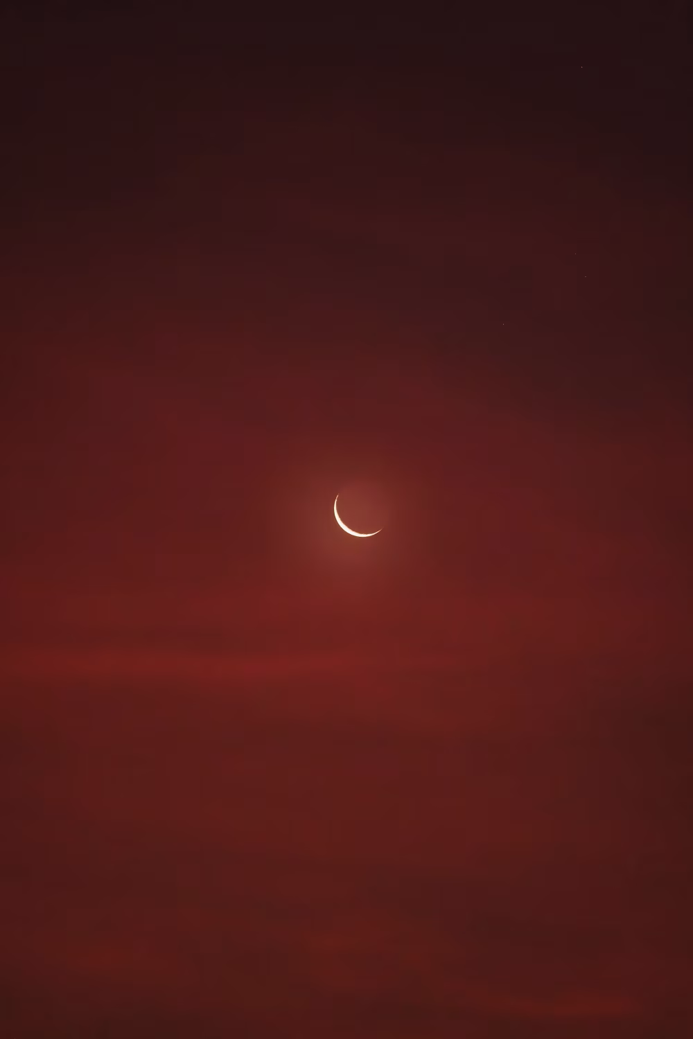 Crescent Moon Over Deep Red Sky At Dusk With Soft Glowing Light And Minimal Composition