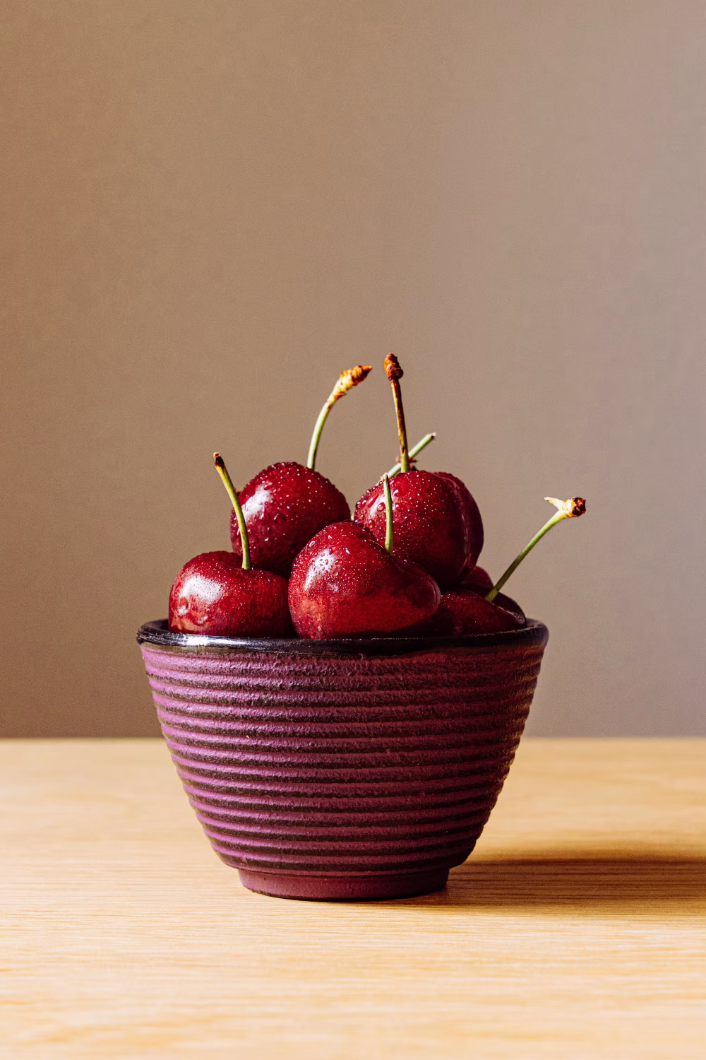 Fresh Red Cherries in a Rustic Ceramic Bowl on Wooden Table With Neutral Background