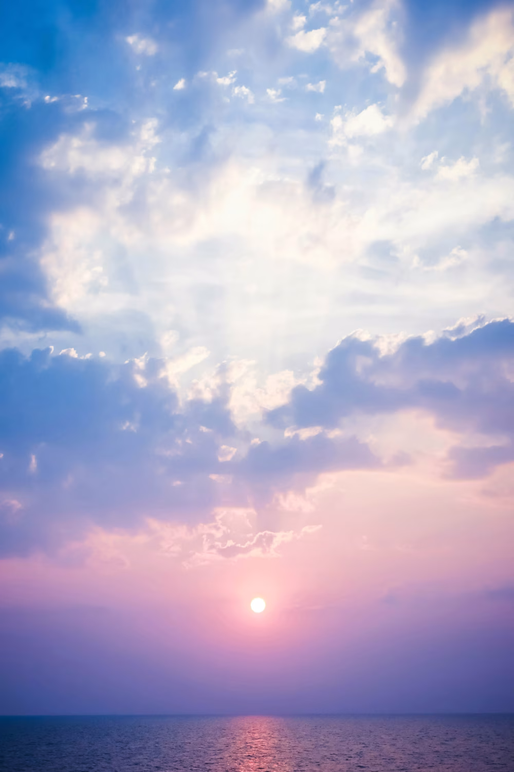 Pastel Sunset Over Calm Ocean With Sun Reflection, Dramatic Clouds and Tranquil Horizon