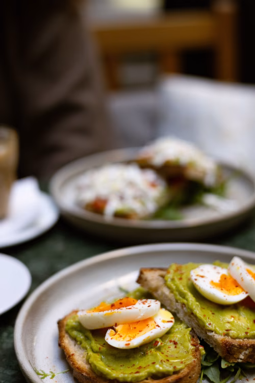Avocado Toast With Sliced Soft Boiled Eggs on Rustic Bread Served at Brunch Cafe