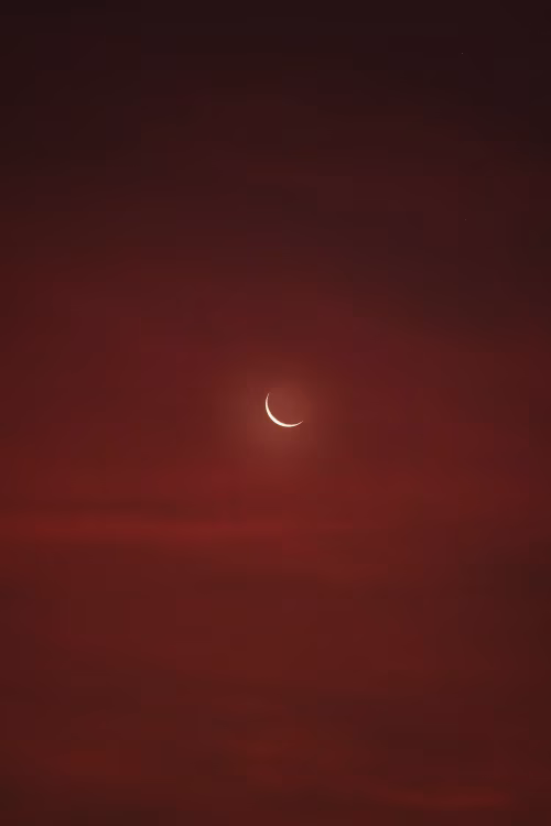Crescent Moon Over Deep Red Sky At Dusk With Soft Glowing Light And Minimal Composition