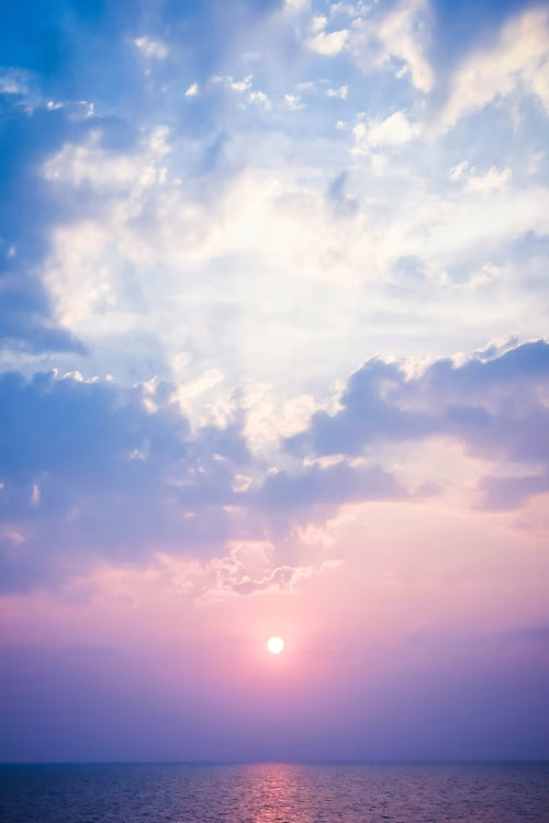 Pastel Sunset Over Calm Ocean With Sun Reflection, Dramatic Clouds and Tranquil Horizon